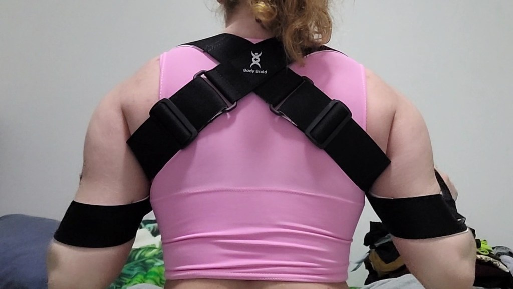 Me from the back, wearing the arm braid over a pink chest binder with my arms down.